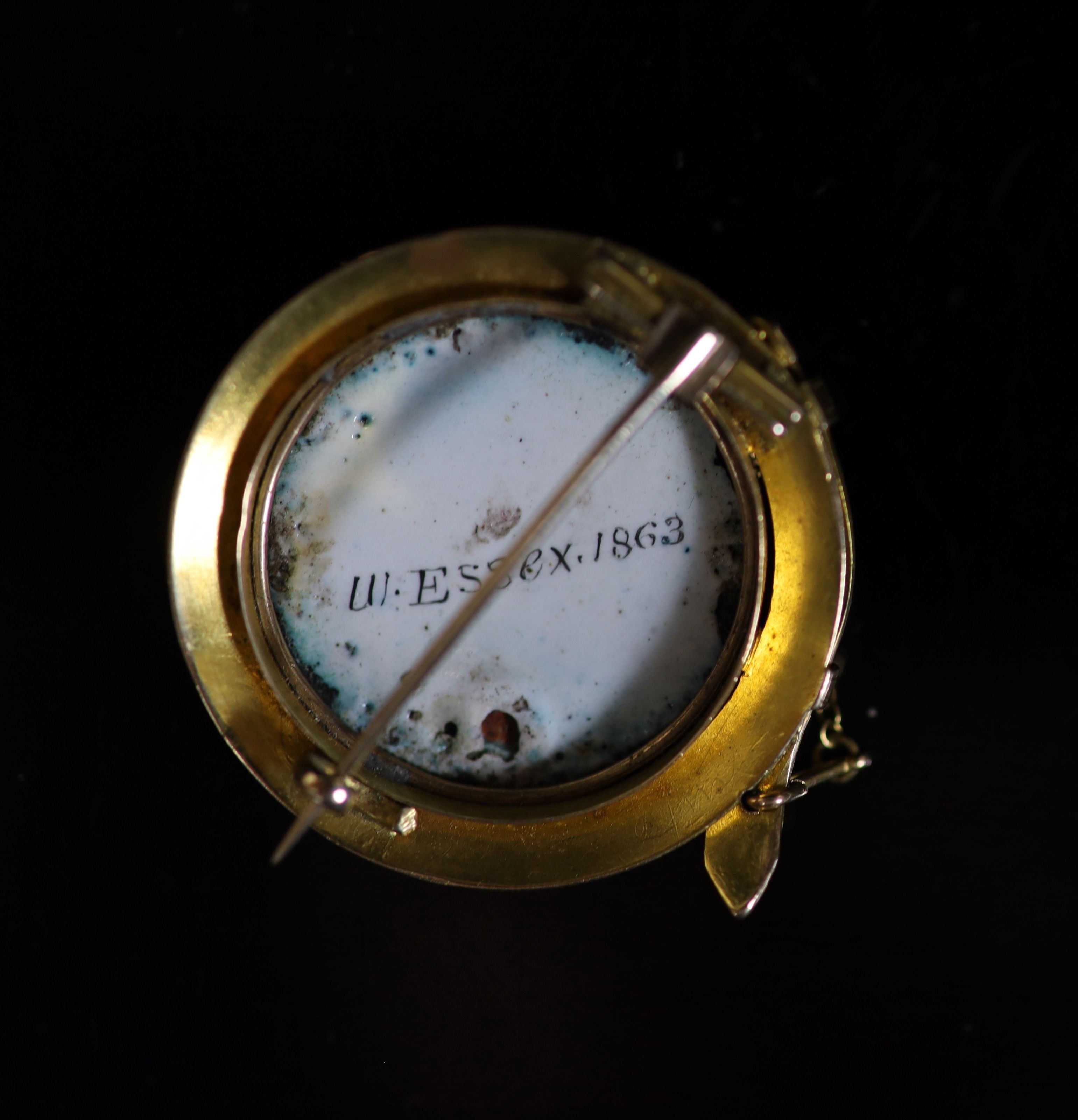 A Victorian gold and enamel circular brooch, decorated with the head of a dog, inscribed verso 'W. Essex, 1863'